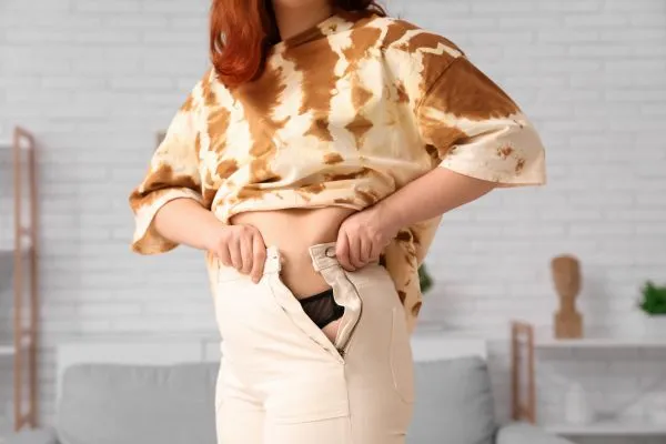Image of woman trying to do her trousers up after pregnancy weight gain Atherstone
